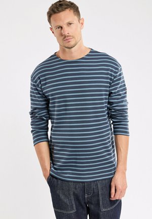 T-shirt à manches longues de couleur bleu marine foncé avec des rayures horizontales bleu clair. Il possède un col rond et une coupe décontractée. La texture du tissu doux est visible.