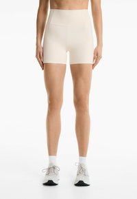 Crème-kleurige high-waisted shorts met een gladde, rekbare textuur. Ze zijn aansluitend en reiken tot halverwege het dijbeen, met een naadloos ontwerp.