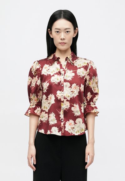 Blouse bordeaux à imprimé floral, texture satin douce, avec des boutons à l'avant et des manches bouffantes froncées. Design ajusté avec un col.