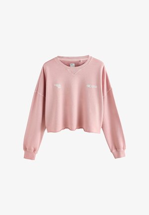 Svetloružový skrátený sweatshir s dlhými rukávmi, širokým výstrihom a bielym potlačným textom. Mäkká textúra a voľný strih.
