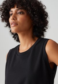Black sleeveless top with a round neckline, made of soft fabric. Features a smooth texture and a fitted design, with no visible patterns or accents.
