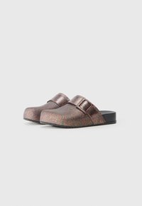 Glittering clogs in rose gold with a smooth, shiny surface. Features a buckle strap and a rounded toe design. Black sole.