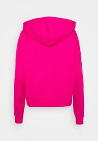 Sudadera con capucha fucsia de diseño cropped, con tejido texturizado y puños acanalados. Acabado suave sin logotipos ni patrones visibles.