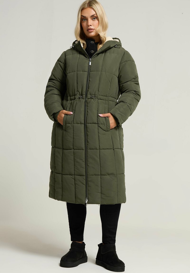 Olivgrön vadderad kappa med huva, med dragkedjestängning, sidofickor och cinchad midja. Mjuk innerfoder och quiltad design.