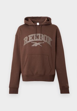 Rjava kapuca z velikim sivim logotipom "REEBOK", kenguru žepom, kapuco na vrvico in rebrastimi manšetami ter spodnjim robom. Material: bombaž.