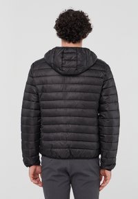 Giacca a vento nera con cappuccio, caratterizzata da un design trapuntato e polsini elasticizzati. Superficie liscia e lucida con una silhouette aderente.