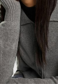 Šedý pletený svetr na zapínání s žebrovanými manžetami a texturovaným vzorem. Jemná látka, nadrozměrný střih, zapínání na knoflíky, pohodlný volný střih.