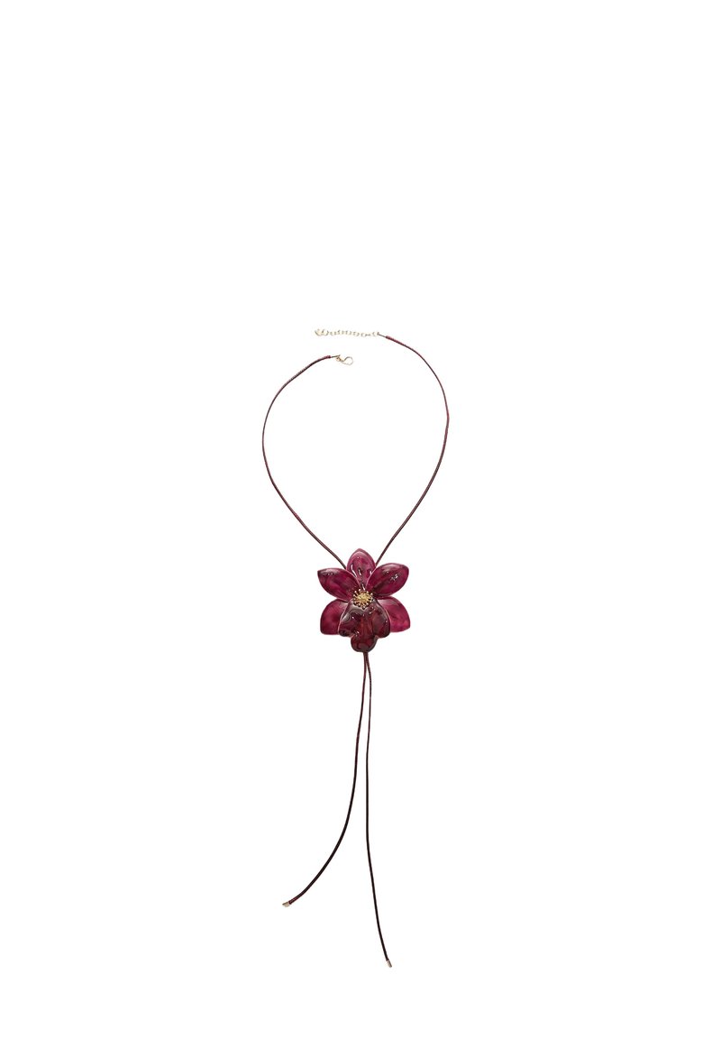 Collana con pendente floreale rosso a sei petali, montata su un cordino marrone con estremità regolabili e particolare chiusura in tono dorato.