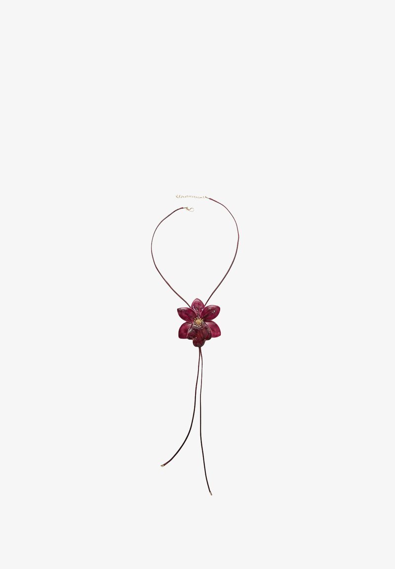Collana con pendente floreale rosso a sei petali, montata su un cordino marrone con estremità regolabili e particolare chiusura in tono dorato.