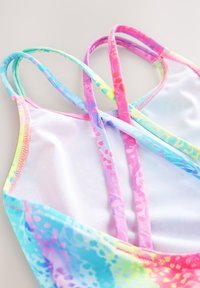 Multicolored swimsuit with thin straps. Features a gradient pattern of pink, blue, and yellow; smooth fabric, and a high-cut leg design.