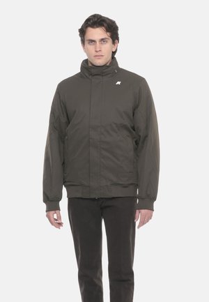 Giacca imbottita verde scuro con collo alto, chiusura con zip e tasche laterali. Presenta polsini elastici e dettaglio con logo riflettente.