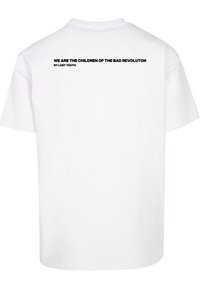 Baltos medvilnės T-shirt su apvalia iškirpte ir trumpomis rankovėmis. Ant nugaros tekstas skelbia: "MES ESAME BLOGOS REVOLIUCIJOS VAIKAI IŠ PRARASTOS JAUNYSTĖS" juodai.