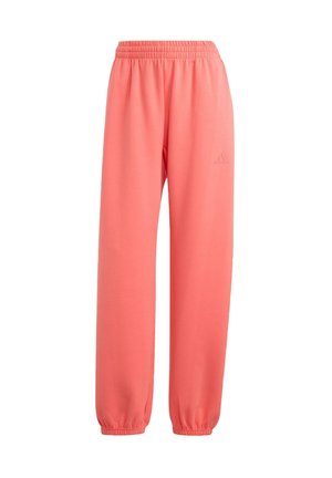 Pantalones deportivos de color coral rosa con cintura elástica, piernas ajustadas y un pequeño detalle de logotipo en relieve cerca de la cintura. Textura suave y lisa.