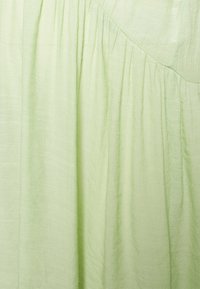 Tecido verde claro com uma superfície suave e texturizada. Apresenta pregas suaves e um design fluido e suave. Adequado para vestuário ou decoração de interiores.