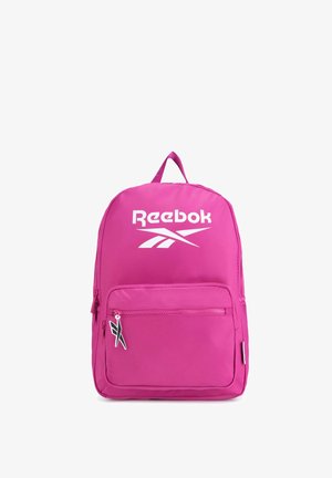 Jasnoróżowy plecak z przednią kieszenią na zamek, białym logo Reebok i czarno-białym suwakiem z logo na białym tle.