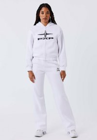 Witte zip-up hoodie met zwart "PXP" logo en taperende joggingbroek. Zacht, soepel stof met ribgebreide manchetten en enkelopeningen. Casual sportkleding.