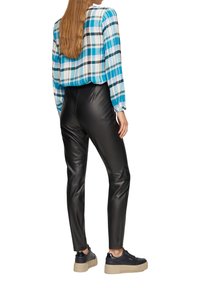 Schwarze Jeans aus Kunstleder, die eng anliegend sind und mit einem blau-weiß karierten, kurzärmeligen Hemd kombiniert werden, das elastische Bündchen und sichtbare Nähte aufweist.