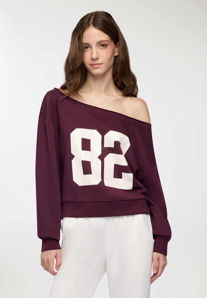 Felpa bordeaux a spalle scoperte con stampa bianca "82"; realizzata in tessuto morbido, presenta maniche lunghe e una vestibilità comoda.