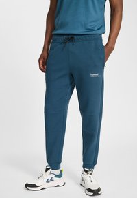 Donkerblauwe sweatpants in een taperende pasvorm, met een elastische tailleband, aantrekkoord, zijzakken en een klein wit logo op de dij.