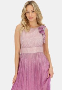 Różowa plisowana sukienka o błyszczącej teksturze z pojedynczym ramiączkiem ozdobionym falbaną. W zestawie regulowany pasek w talii.