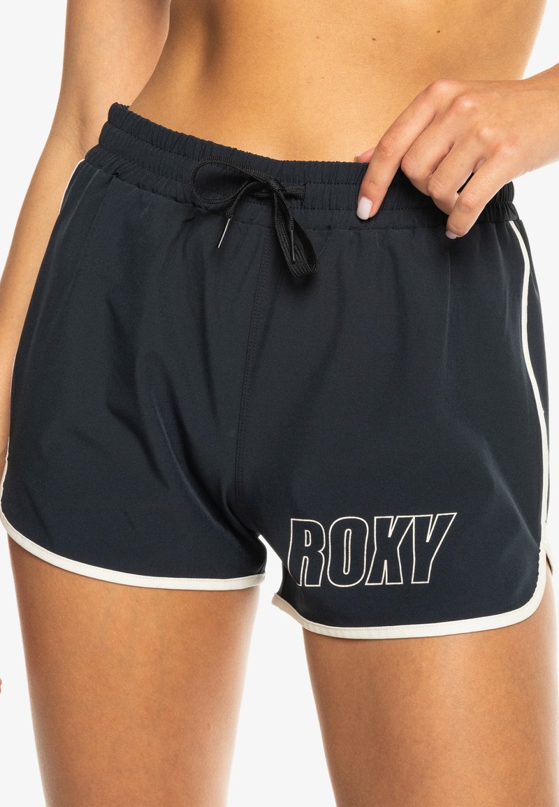 Svart sporty shorts med kontrasterende hvit trim. Elastisk midjebånd med snor. "ROXY"-logo i hvit trykt på den ene siden.