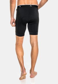 Pantalones cortos deportivos negros con un diseño ajustado, textura suave y longitud hasta medio muslo, que cuentan con un panel de malla en los lados y una cinturilla ancha.