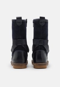 Botas azul marino que combinan ante y cuero, con punta redondeada, correas decorativas en el lateral y un tacón bajo de madera.