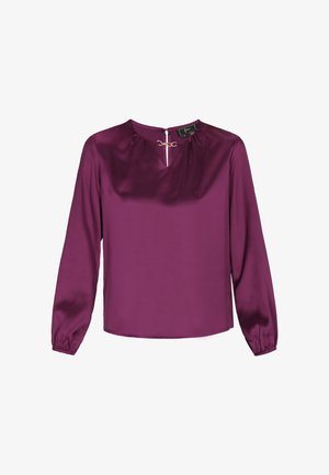 Violeta satīna blūze ar garām piedurknēm, saplacinātu kakla izgriezumu un zelta aksesuāriem priekšā. Gluda tekstūra un vienkāršs dizains.