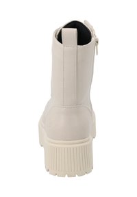 Botas de tobillo de tacón grueso en imitación cuero beige claro, con cremallera lateral, puntera redonda y suela de goma texturizada con ranuras verticales.