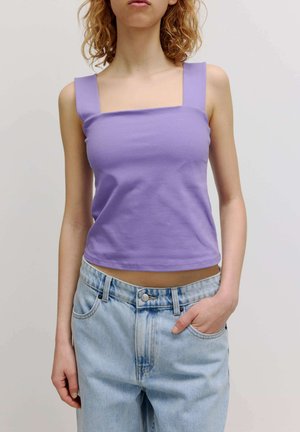 Lila verkürztes Tanktop mit breiten Trägern und einem quadratischen Ausschnitt, kombiniert mit hellblauen hochtaillierten Jeans. Glatte Baumwollstruktur.