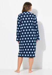 Lunga vestaglia blu navy con grandi pois azzurri, dotata di maniche lunghe e colletto, realizzata in tessuto morbido e che arriva a metà polpaccio.