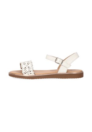Sandalias de cuero blanco con un diseño cortado y cinta ajustable en el tobillo. Suela plana con un fondo de goma marrón y detalles texturizados.