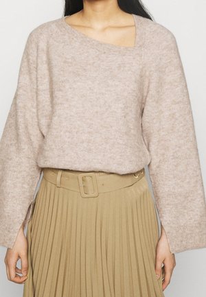 Hellbeige, grob gestrickter Pullover mit asymmetrischem Ausschnitt, kombiniert mit einem plissierten beigen Rock und einem passenden Gürtel. Glatte Textur.