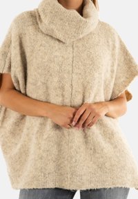 Beige, zachte wollen poncho met een colkraag. Heeft een losse pasvorm en korte mouwen, een gestructureerd oppervlak en een rechte zoom.