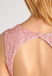 Rosa paljettbelagd klänning bak med rund utskärning, mjukt tyg och knäppning vid halsen. Detaljerad textur och glans synlig.