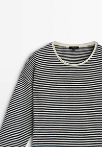 Maglione a righe bianche e nere con scollatura tonda, texture a coste e colletto crema a contrasto. Maniche lunghe, design casual.