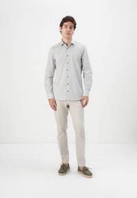 Light gray patterned button-up shirt, slim fit, paired with cream trousers and green lace-up shoes. Smooth texture, subtle print details.