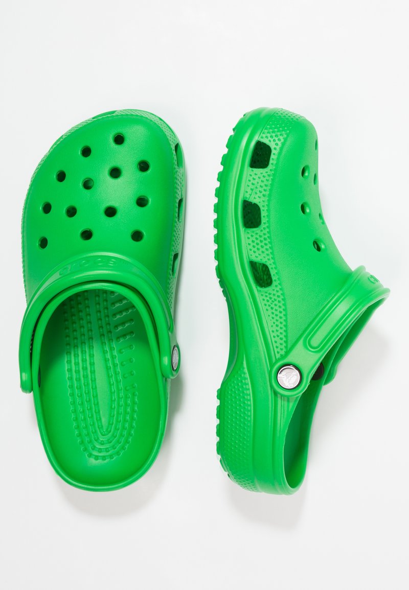 Zielone klapki wykonane z elastycznego plastiku, z otworami wentylacyjnymi, paskiem z tyłu i teksturowanym wnętrzem dla wygody.