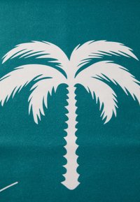 Tirkizna tkanina s velikim bijelim motivom palme. Palma ima teksturirane listove i detalj u obliku cik-caka na deblu.
