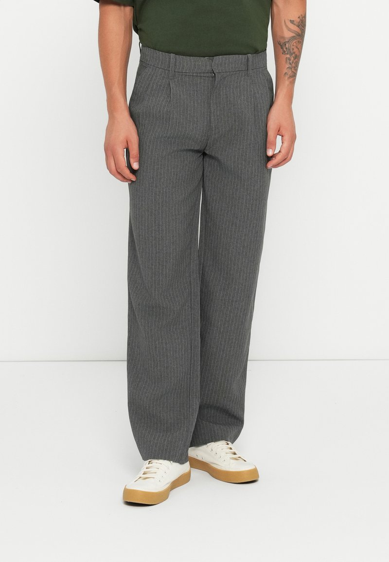 Gray pinstriped trousers with a relaxed fit, made of woven fabric, featuring a flat front and a standard waistband. Worn with white sneakers.