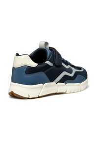 Zapatilla de deporte en azul marino y azul claro con suela de goma, acentos de gamuza y una correa de gancho y bucle. Presenta una pestaña trasera y detalles en blanco.
