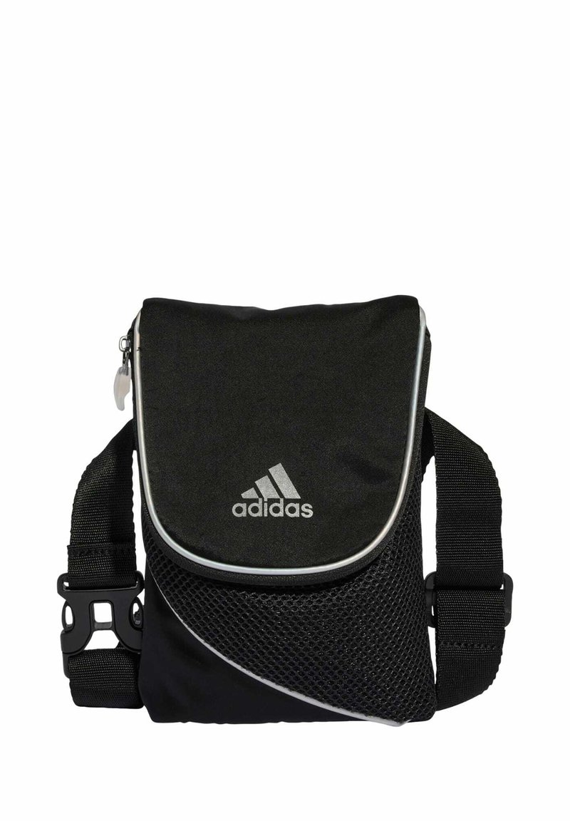Čierna kabelka Adidas cez rameno so zipsovým uzáverom, sieťovanými panelmi, nastaviteľným popruhom a strieborným logom na prednej strane. Kompaktný dizajn.