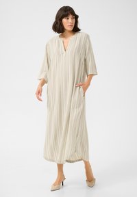 Abito maxi a righe beige con scollatura a V, maniche a tre quarti e tasche laterali; realizzato in tessuto leggero con una superficie liscia.