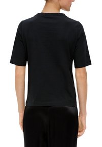 Zwart katoenen t-shirt met een eenvoudig ontwerp, voorzien van korte mouwen en een ronde hals. De stof lijkt glad en heeft een comfortabele pasvorm.