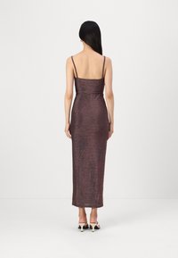 Robe midi bourgogne métallisée avec des fines bretelles, silhouette ajustée et texture lisse. Longueur mi-mollet, ourlet arrière légèrement arrondi.