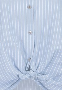 Light blue button-up shirt with white vertical stripes, featuring a knotted front detail and silver buttons for fastening. Soft fabric texture.
