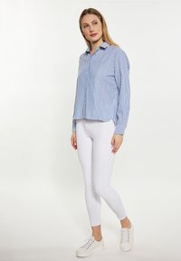 Lichtblauw en wit gestreepte button-up shirt met een kraag, gecombineerd met witte skinny jeans en witte sneakers. Soepele stof, relaxte pasvorm.