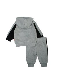 Sweat à capuche gris avec manches noires et pantalon de survêtement gris assorti. Le matériau semble doux avec des poignets côtelés et une poche kangourou.