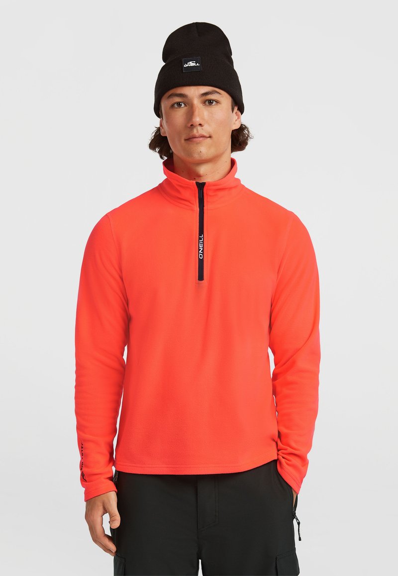 Meeste fliisipullover heledas oranžis, millel on kõrge krae, neljandikukeelega esiküljel ja must brändingutähtsus lukul.