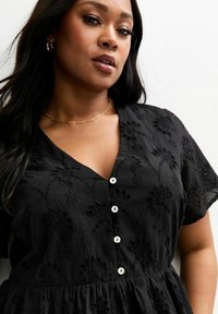 Black dress with short sleeves, v-neck, embroidered floral pattern, and front buttons. Soft fabric with a gathered waist for a relaxed fit.